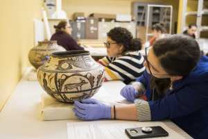 Victoria looking at an old Zuni pot in museum study space.